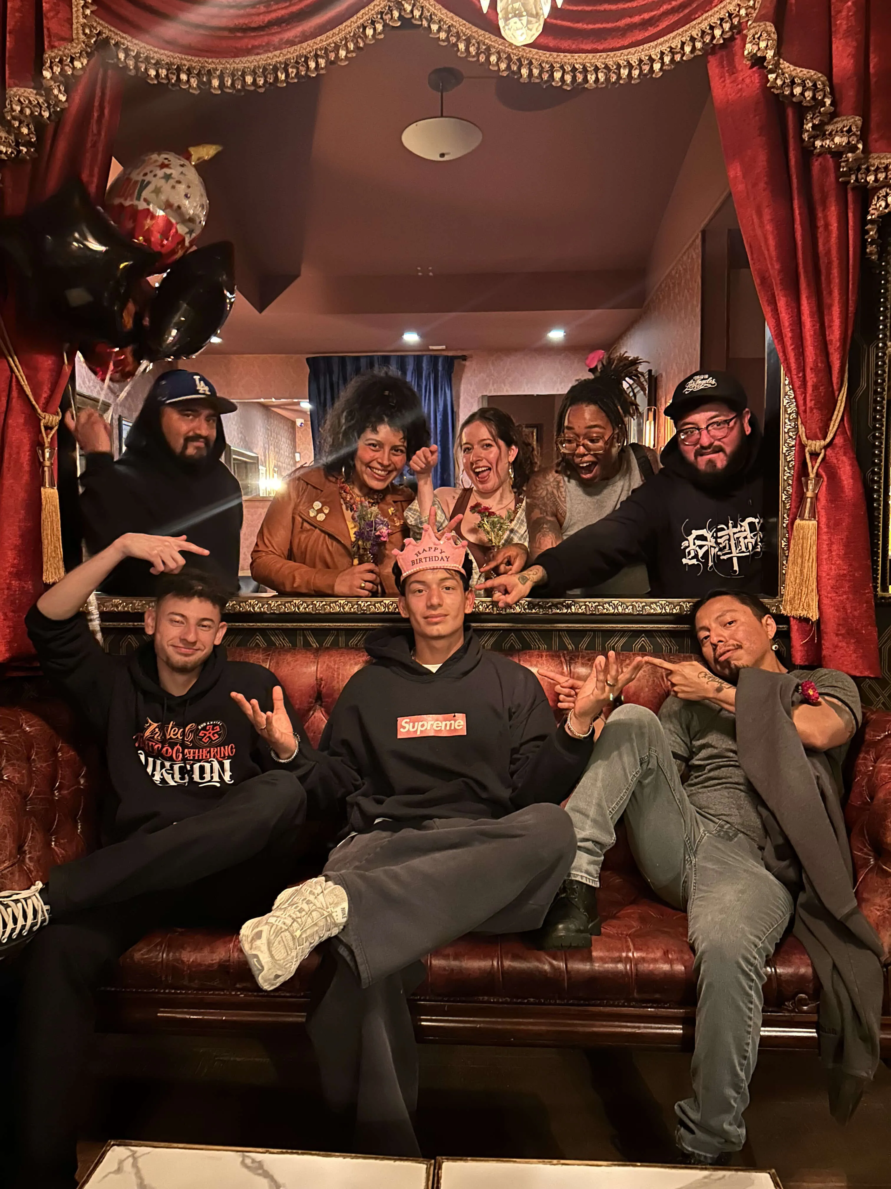 Tattoo artists and studio crew celebrating together on a vintage leather sofa inside a tattoo parlor